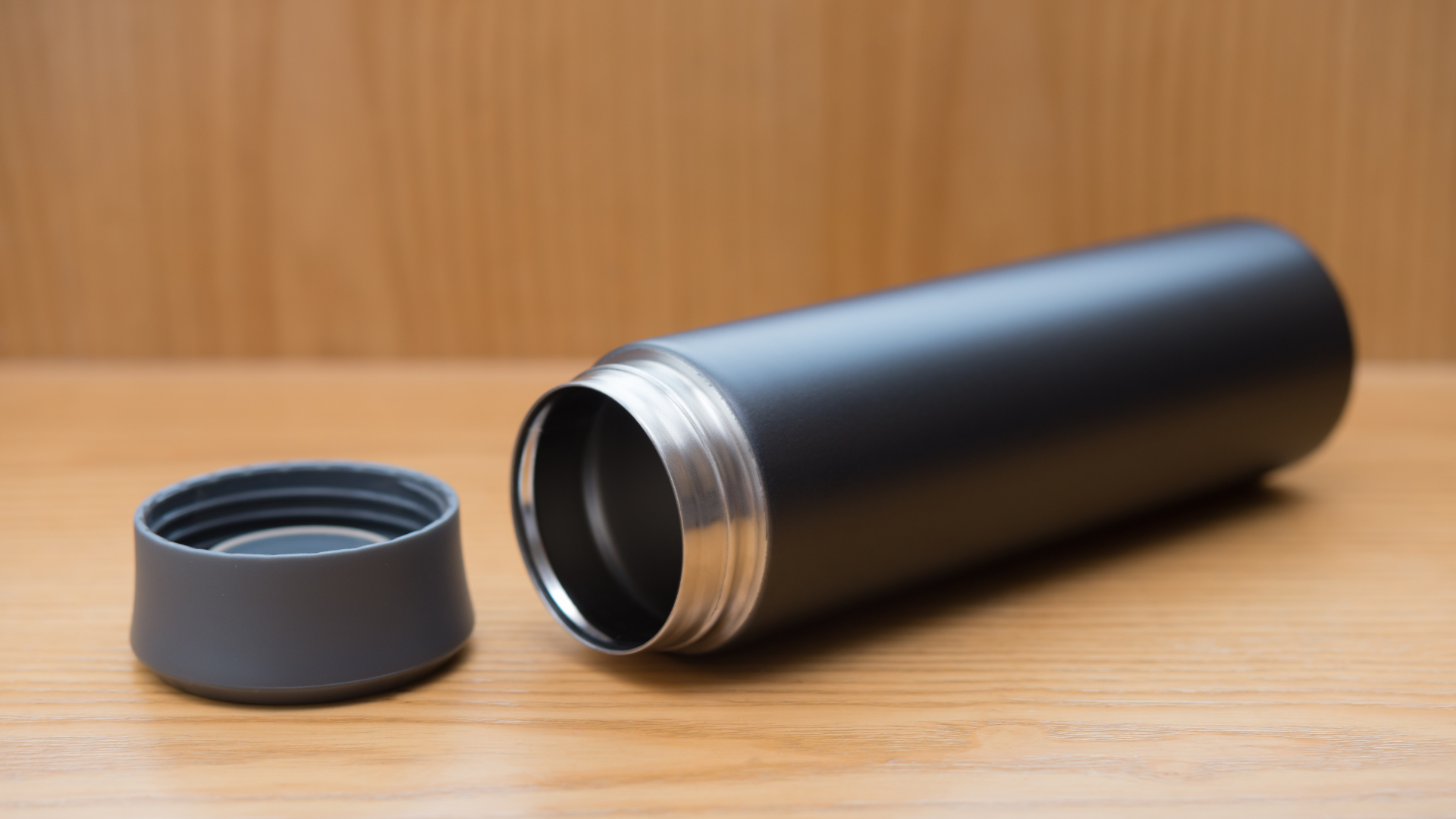 An open gray tumbler on a wooden surface