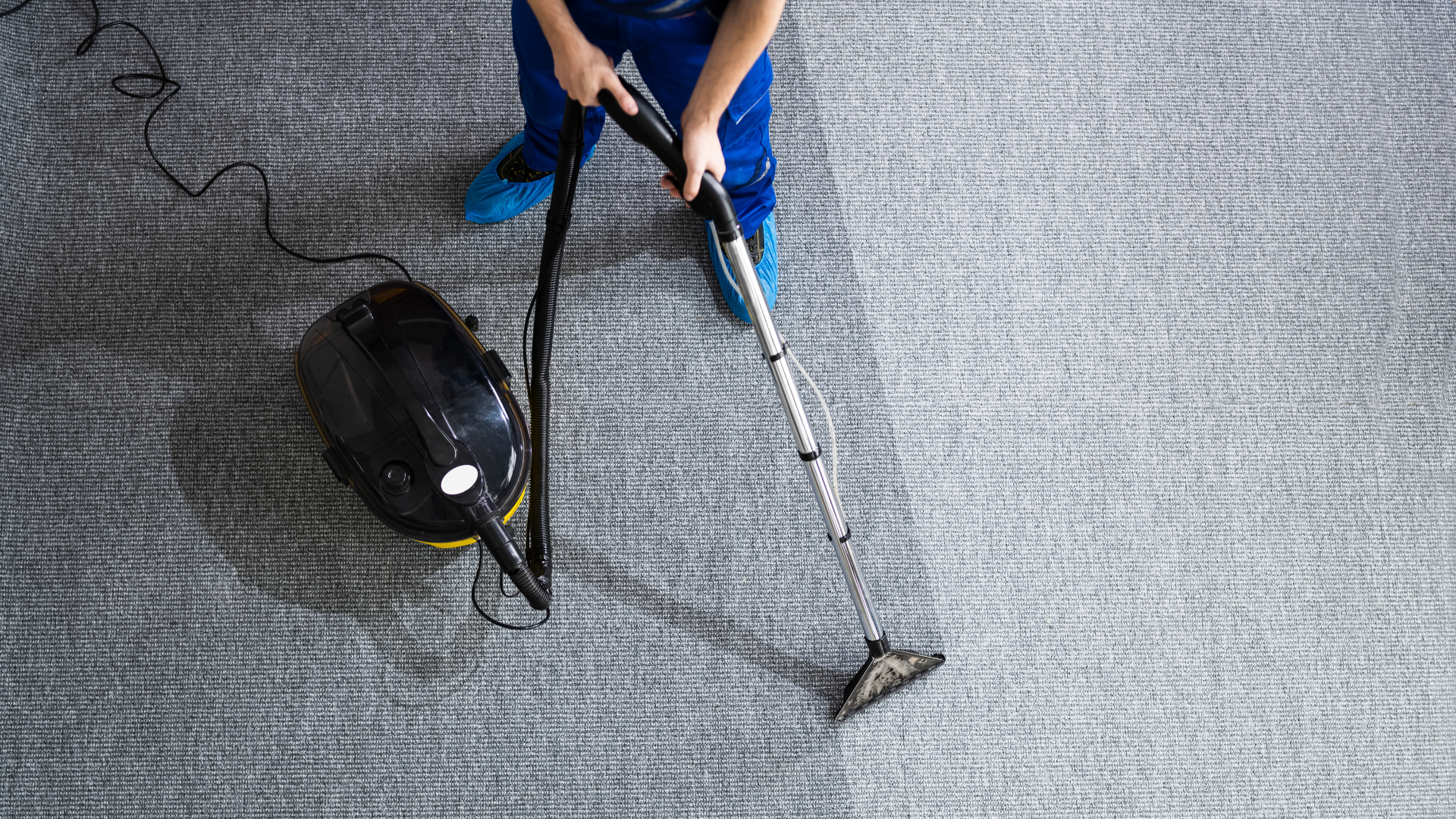 Person cleaning a gray carpet with a bagless vacuum cleaner in a living room