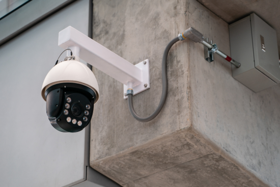 Mounted black home security camera positioned on the corner of a building, capturing a wide-angle view