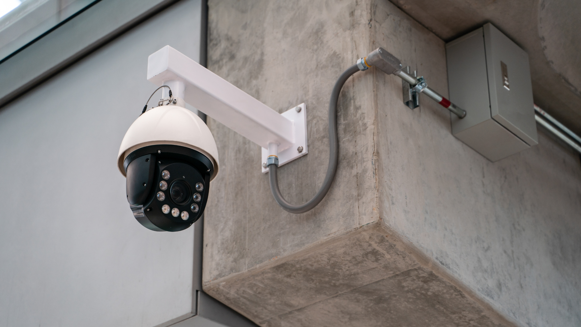 Mounted black home security camera positioned on the corner of a building, capturing a wide-angle view