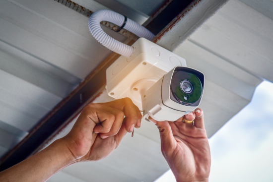 Repair man installing a security camera on a gray roof