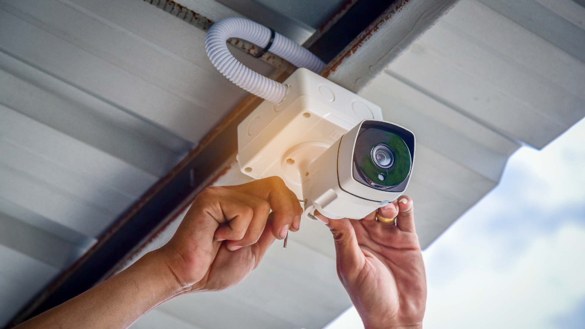 Repair man installing a security camera on a gray roof