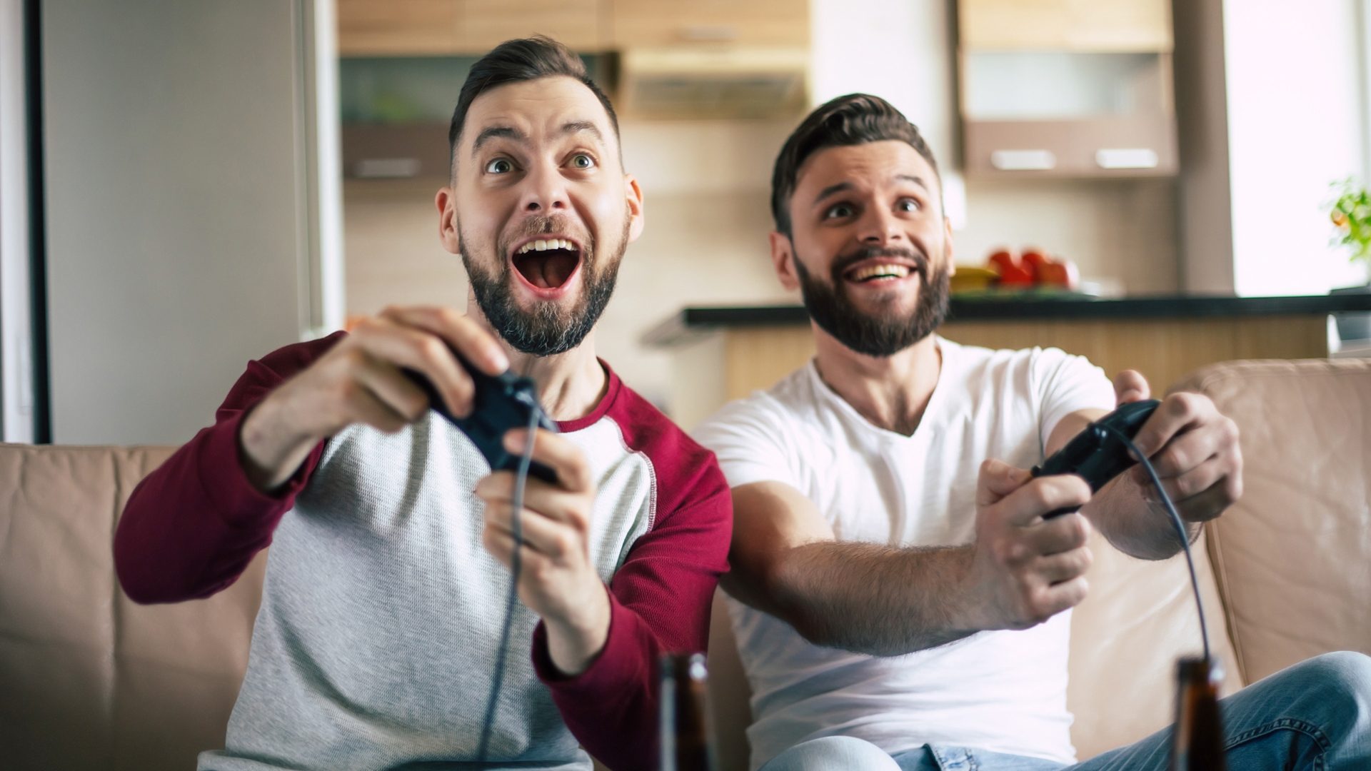 Two excited men playing video games on a console at home, enjoying a gaming session