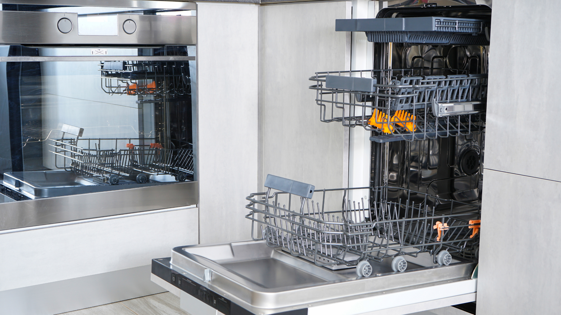 An open dishwasher in a modern stainless steel kitchen.