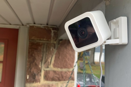 White compact security cameras placed on a wall in an outdoor garage.