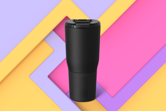 A black tumbler cup with a closed lid, set against a colorful, layered background featuring yellow, pink, and purple geometric shapes.