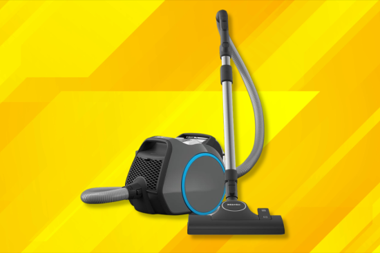 A canister vacuum cleaner with a sleek black and blue design, placed against a vibrant yellow background with geometric patterns.