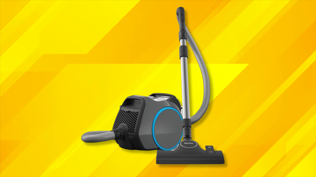 A canister vacuum cleaner with a sleek black and blue design, placed against a vibrant yellow background with geometric patterns.