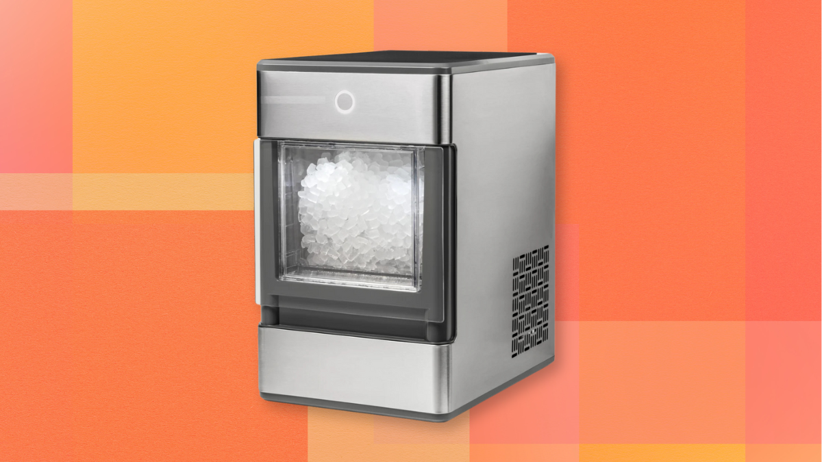 A stainless steel countertop ice maker filled with ice, set against a vibrant orange background with subtle geometric patterns.