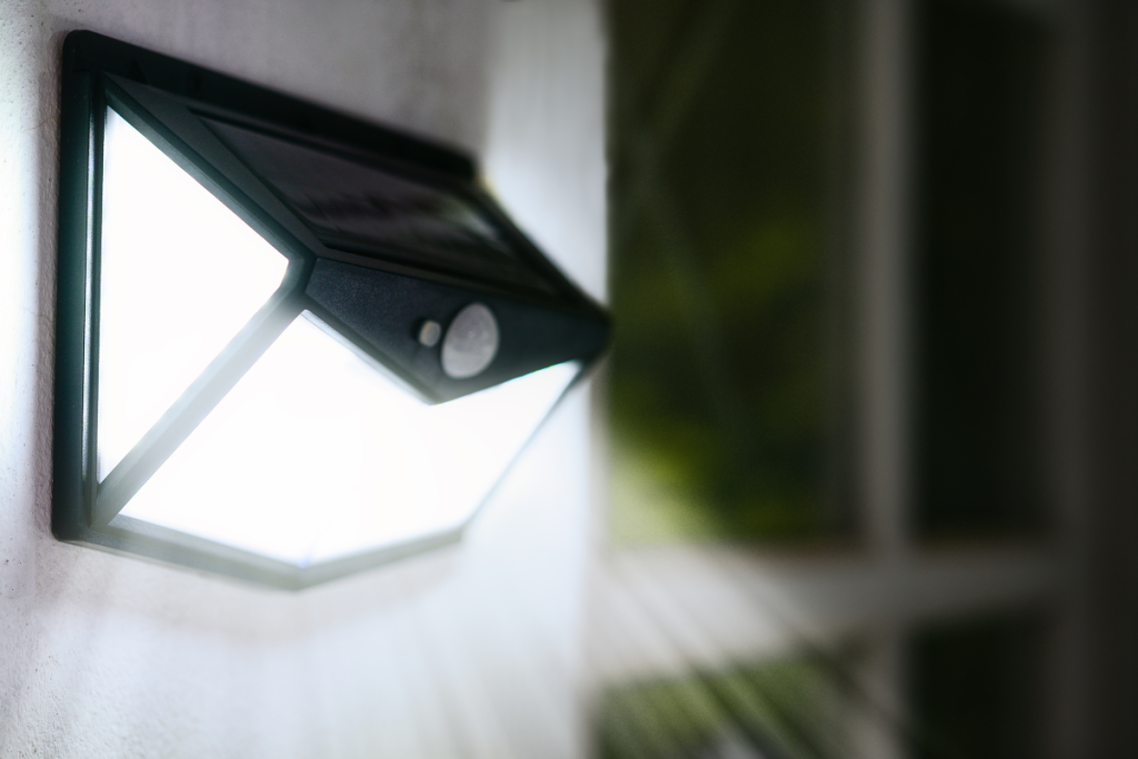 Wall-mounted solar motion sensor light emitting bright white light at night.