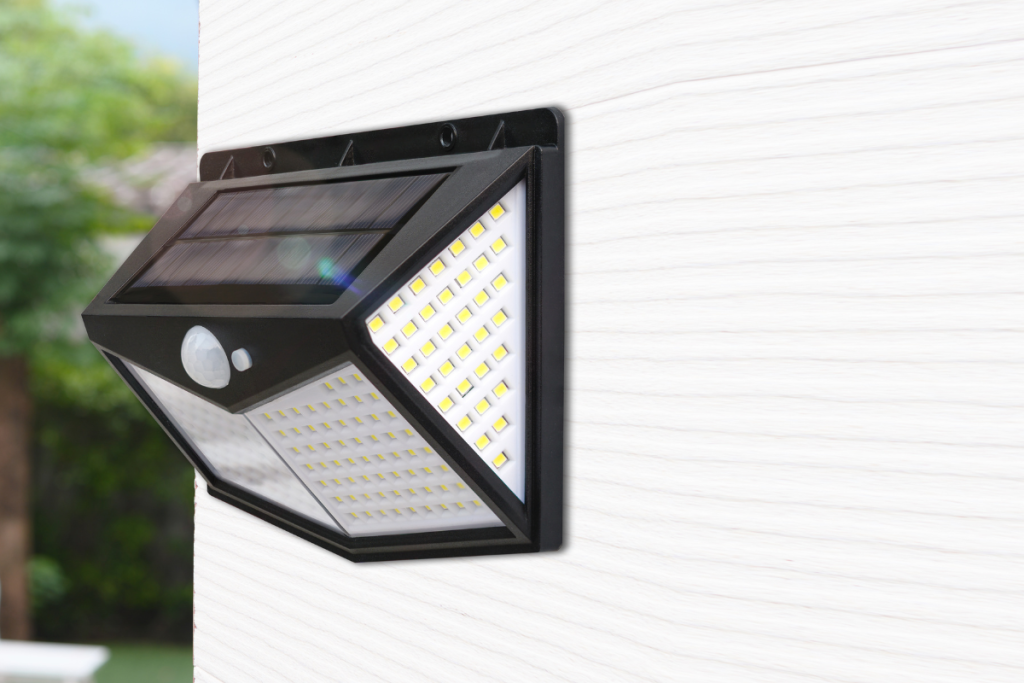 Wall-mounted solar LED light with motion sensor installed on a white exterior surface.