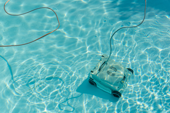 An underwater robotic pool cleaner vacuuming the bottom of a swimming pool.