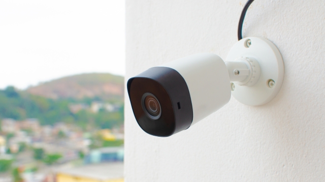 Close-up of a white smart home security camera with a sleek design against a neutral background