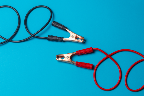 This image showcases a set of jumper cables with red and black clamps, used for jump-starting car batteries.