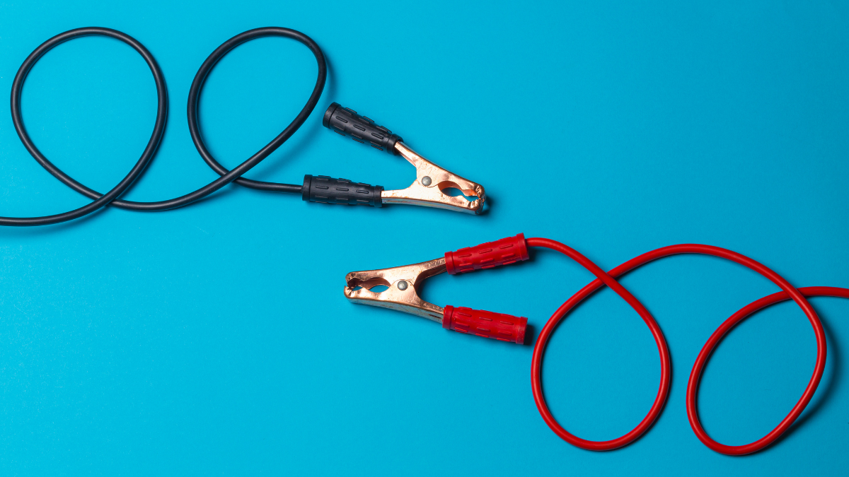 This image showcases a set of jumper cables with red and black clamps, used for jump-starting car batteries.