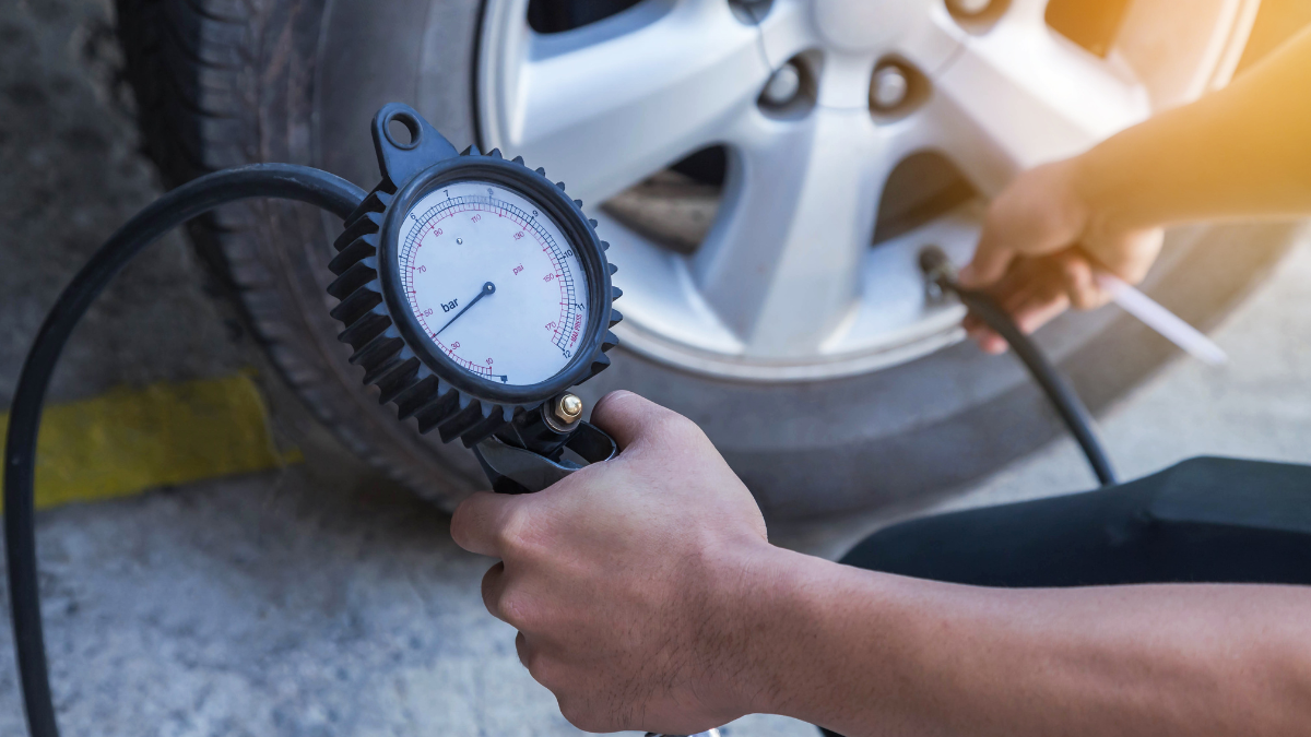 This image features a person checking the tire pressure of a vehicle using a tire pressure gauge.