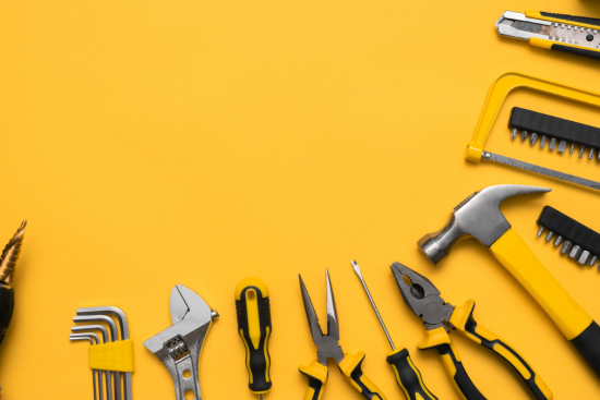 This image displays a vibrant arrangement of hand tools against a bright yellow background.