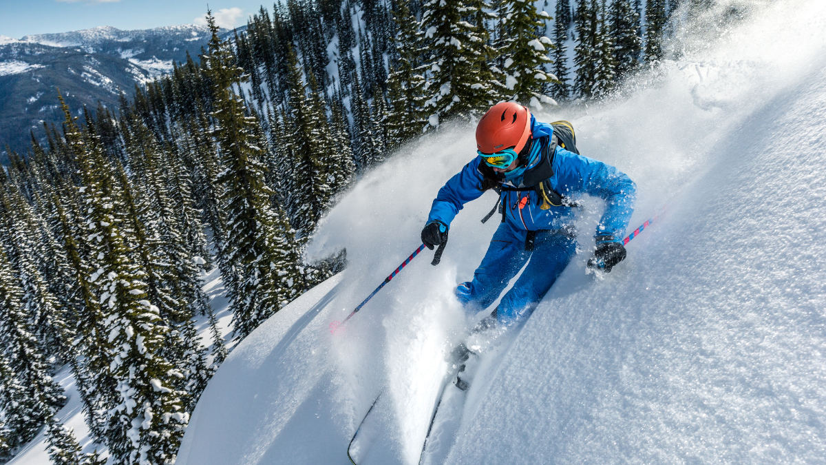 An adrenaline-filled moment of a skier in vibrant blue gear gliding through fresh powder snow on a mountain slope, surrounded by towering pine trees and a scenic winter landscape.
