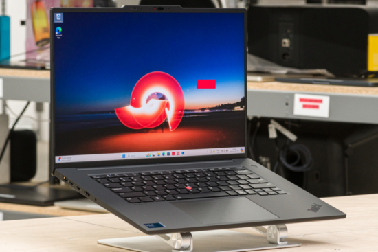 A sleek laptop with a vibrant display showing a red and blue abstract background, set on a modern stand in a tech workspace.