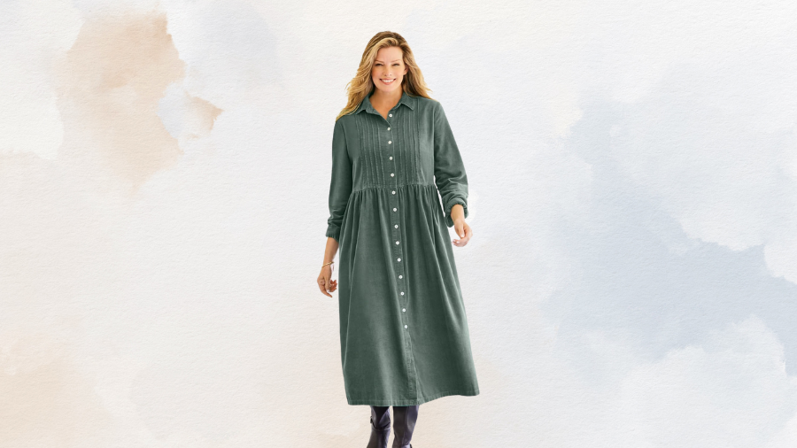 A woman wearing a long green button-down dress with long sleeves, standing against a soft pastel background.