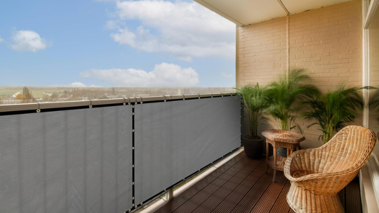 A cozy balcony with a privacy screen, rattan chair, and potted plants, offering a relaxing outdoor space with a scenic view.