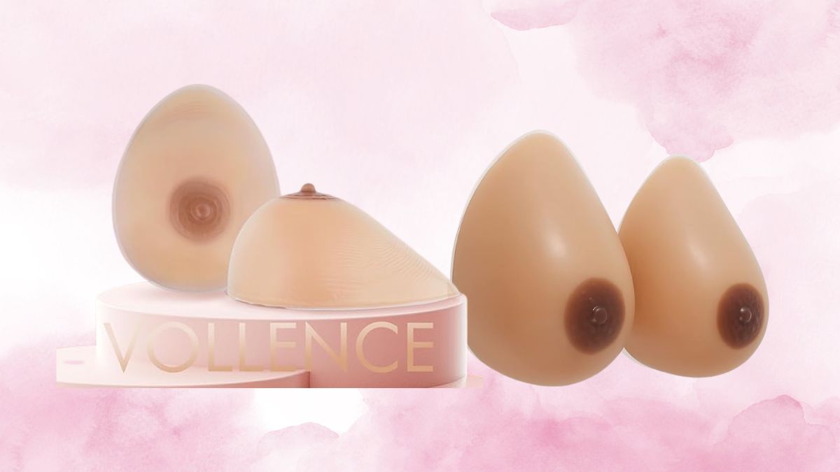 A set of Vollence silicone breast forms in different shapes and sizes, displayed on a pink stand with a soft background.