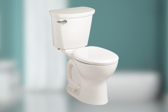 A white American Standard Cadet Pro two-piece toilet with an elongated bowl and a sleek design, shown in a clean bathroom setting with a light blue background.