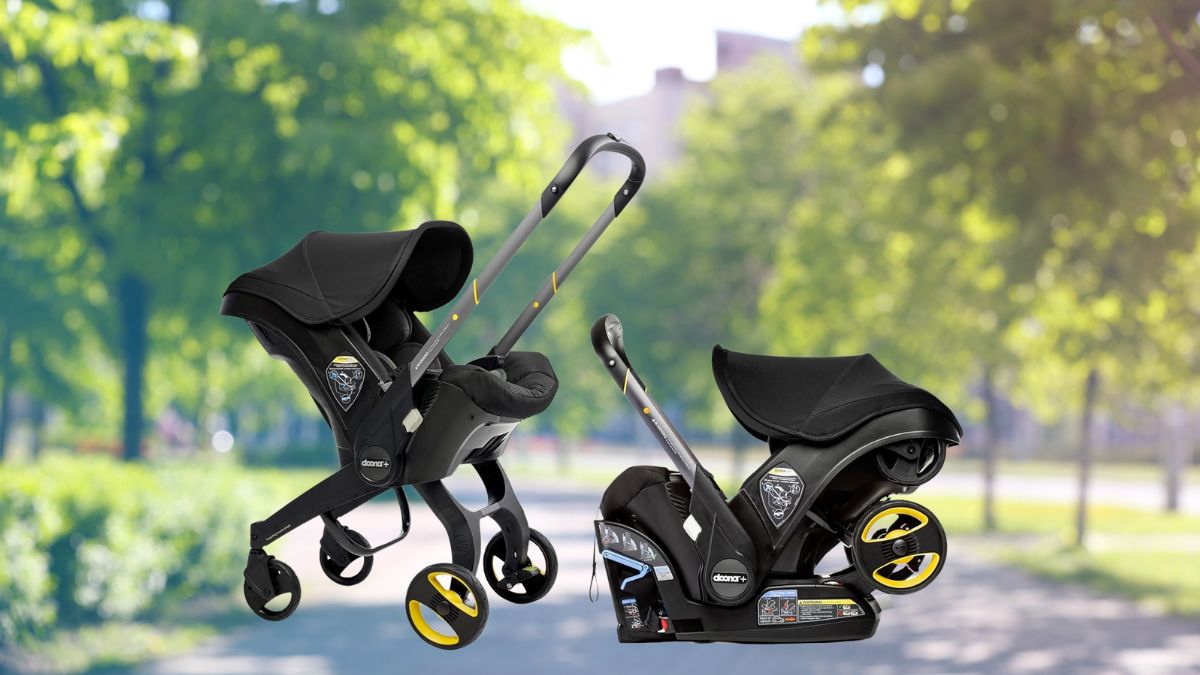 A black Doona car seat and stroller shown in both car seat mode and stroller mode on a park pathway with green trees in the background.