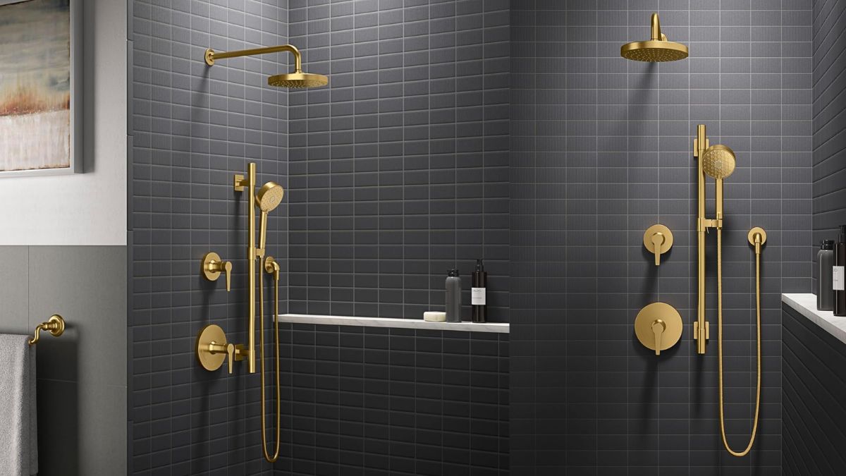 A modern bathroom with dark tiled walls features a gold shower system with a rain showerhead, a hand shower, and matching fixtures.