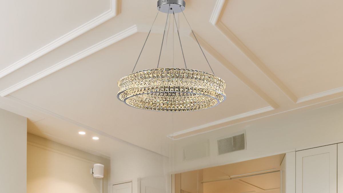 A modern crystal chandelier with two glowing rings hangs from the ceiling in a bright, stylish room.
