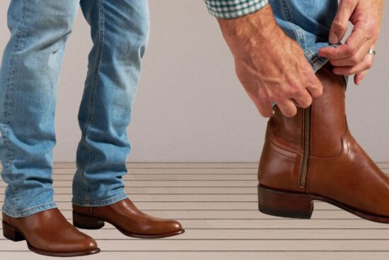 A person wearing brown leather western boots with blue jeans, showing a side zipper for easy wear.