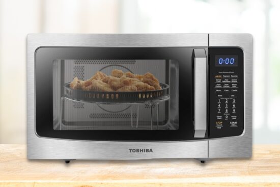 A stainless steel Toshiba microwave with an air fryer function, cooking crispy fries inside.