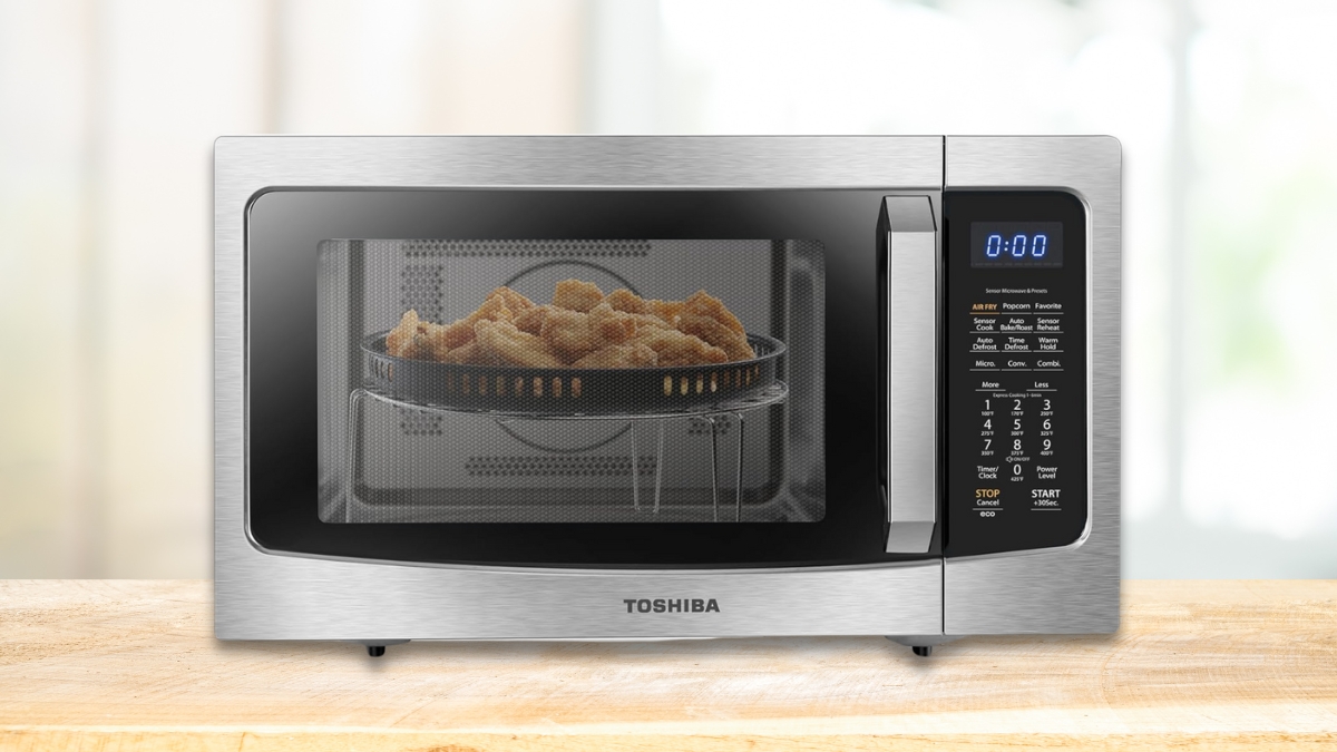 A stainless steel Toshiba microwave with an air fryer function, cooking crispy fries inside.