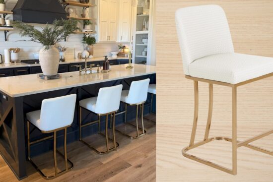 A modern kitchen with a black island features white kitchen bar stools with gold metal legs, a cushioned seat, and a curved back, adding elegance and comfort to the space.