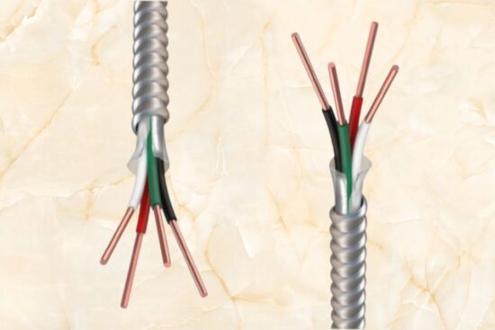 A close-up image of a metal clad cable with exposed copper conductors, color-coded insulation, and a protective aluminum armor for electrical wiring.