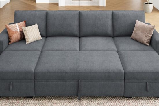 A modern gray sectional sofa with a pull-out bed feature, decorated with soft pillows in a cozy living space.