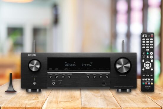 Denon AVR-S760H 7.2-channel 8K home theater receiver with remote and antenna shown on a wooden table in a home setting.
