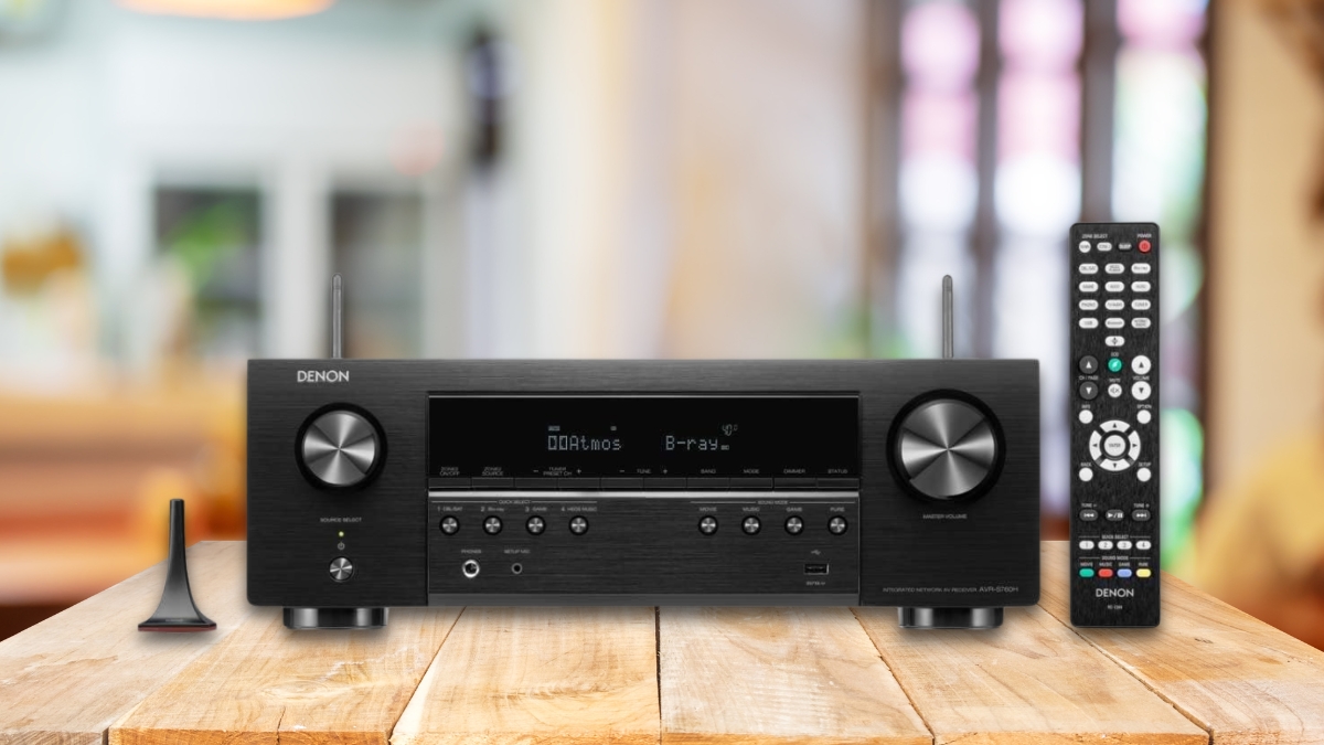 Denon AVR-S760H 7.2-channel 8K home theater receiver with remote and antenna shown on a wooden table in a home setting.