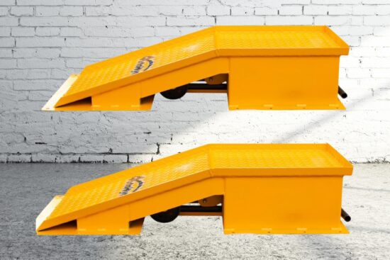 A pair of heavy-duty yellow car ramps with a textured surface, placed against a brick wall background.