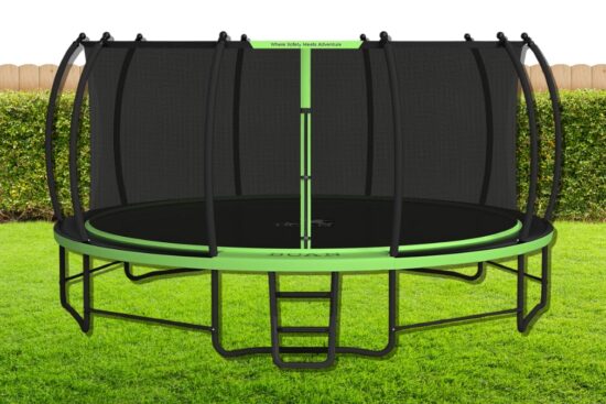 A round outdoor trampoline with a safety net, green frame, and ladder, set on a grassy lawn with a wooden fence in the background.