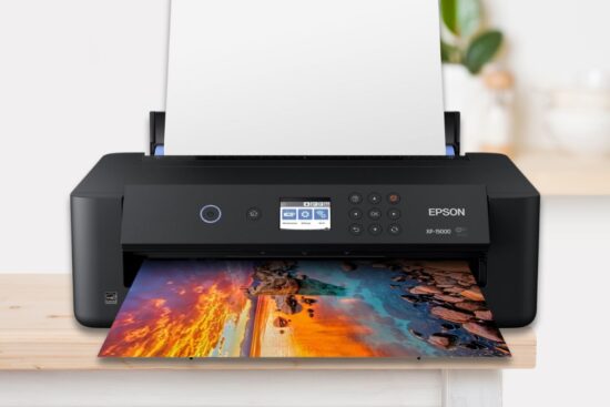 Epson Expression Photo HD XP-15000 printer printing a colorful wide-format photo on a wooden desk.
