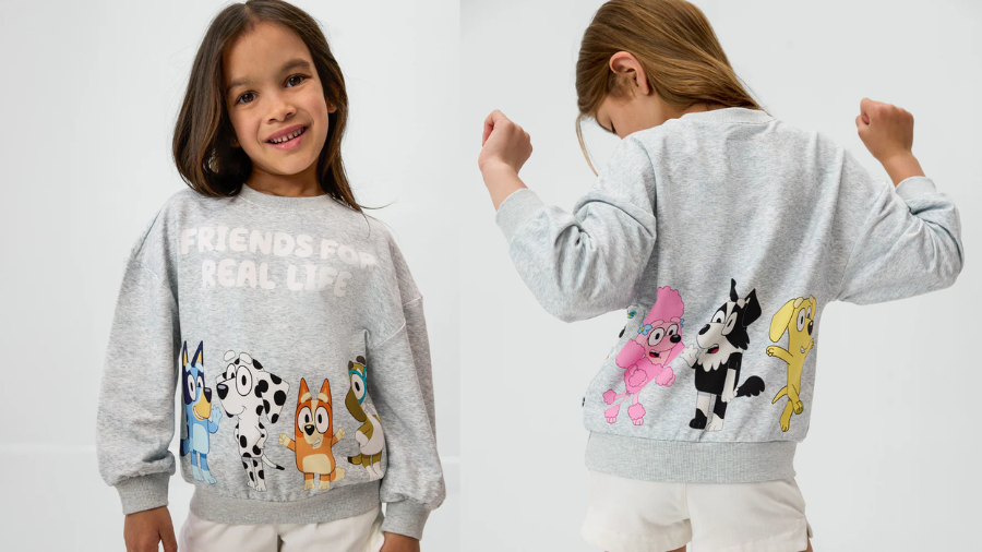 A young girl modeling a gray sweatshirt with cartoon animal characters and the text “Friends For Real Life” on the front and more colorful characters on the back.