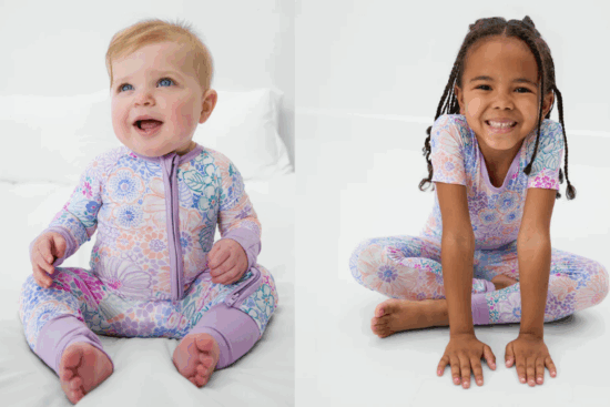 A baby and a young girl wearing matching pastel floral-patterned pajamas, sitting and smiling in a bright, white setting.