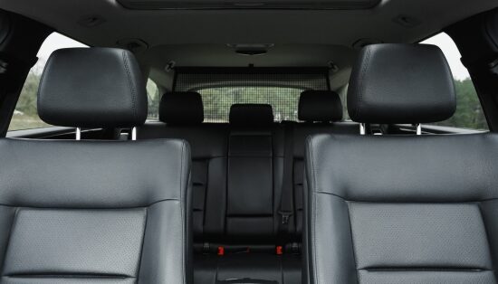 Interior view of a car with black low-back vinyl seats and headrests, showing front and rear seating layout.