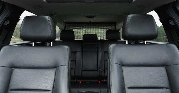 Interior view of a car with black low-back vinyl seats and headrests, showing front and rear seating layout.