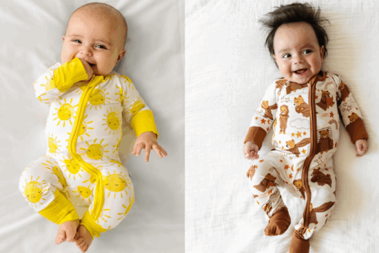 Two babies lying on white sheets, one in a yellow sun-patterned onesie and the other in a brown animal-themed onesie.