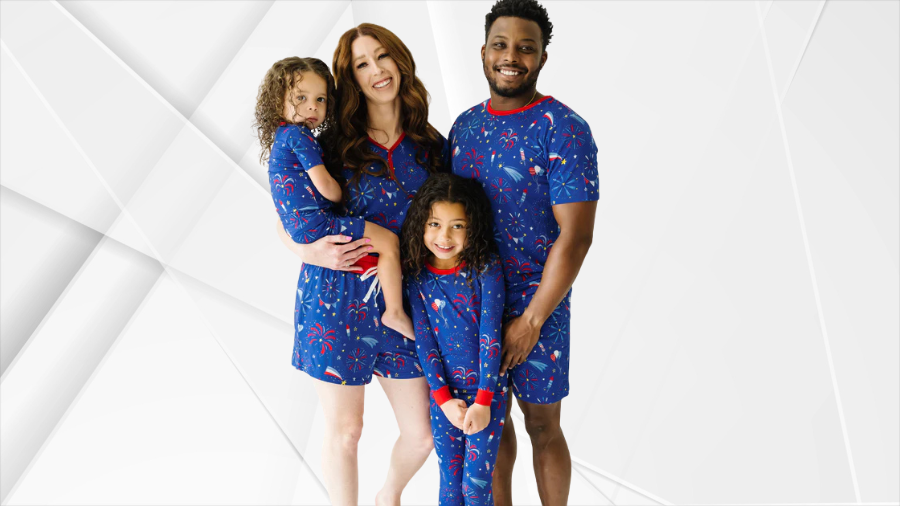 A smiling family wearing matching blue pajamas with red, white, and blue fireworks print for Independence Day.