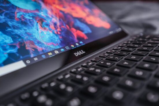 Close-up of a Dell laptop screen and keyboard showing colorful graphics and Windows taskbar.