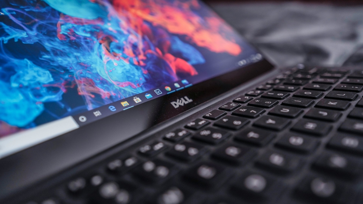 Close-up of a Dell laptop screen and keyboard showing colorful graphics and Windows taskbar.