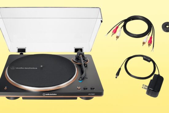 Audio-Technica wireless turntable with dust cover, RCA cables, power adapter, and 45 RPM adapter on a yellow background.
